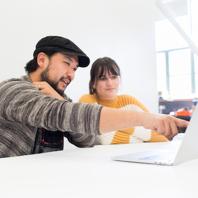 An engaged LMU design instructor working with a student on laptop computer.